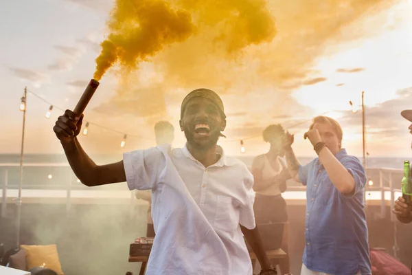 Joven hombre africano extático con galleta de humo amarillo —  Fotos de Stock
