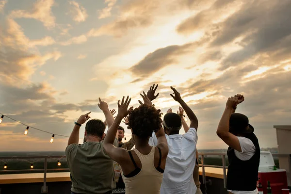 Vista trasera de amigos disfrutando de una fiesta al aire libre en la parte superior del techo —  Fotos de Stock