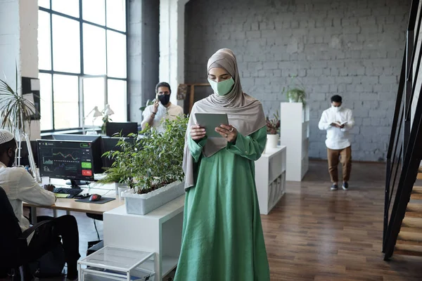 Молодая бизнесвумен в хиджабе ходит по столам в большом офисе — стоковое фото