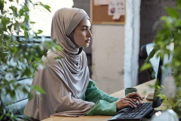 Perempuan Muslim serius dalam jilbab melihat layar komputer — Stok Foto