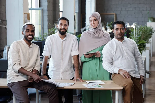 Четыре молодых межкультурных предпринимателя, стоящих на рабочем месте в большом офисе — стоковое фото