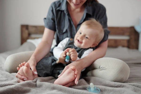Glimlachende Jonge Moeder Zitten Bed Spelen Met Babys Voeten Slaapkamer — Stockfoto