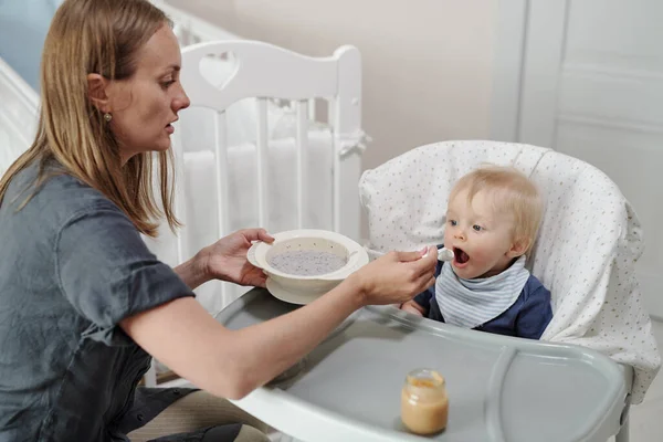 Sério Jovem Mãe Caucasiana Sentado Frente Bebê Alimentá Com Colher — Fotografia de Stock
