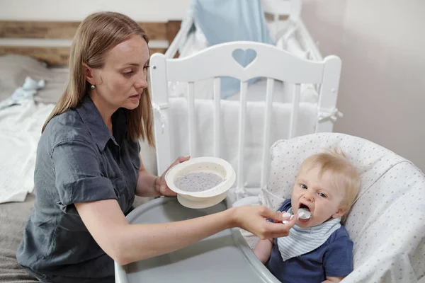 Serious Careful Young Mother Sitting Front Baby Bedroom Giving Porridge — Stock Photo, Image