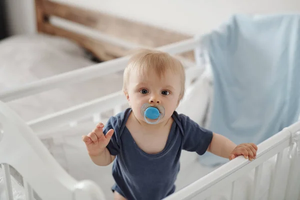 유아용 침대에 고무젖꼭지를 심각하고 귀여운 아이의 — 스톡 사진
