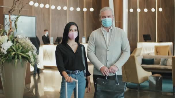 Coronavirus Sırasında Seyahat Eden Maskeli Modern Otel Lobisinde Bavullarıyla Kameraya — Stok video