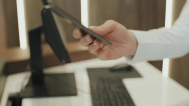 Otel müşterilerine pasaport ve anahtar kartı veren tanınmayan bir resepsiyonistin yavaş yavaş yakın çekimi.