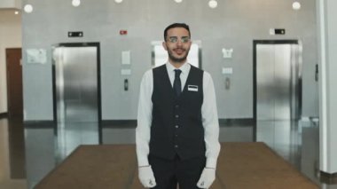 Keyifli erkek otel müdürünün, modern lüks otellerde konukları gezdirirken orta ölçekli bir fotoğrafı.