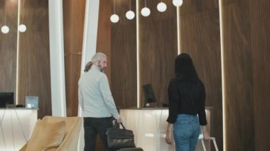 Bavullu modern çiftin orta sınıf bir otele giriş yapmak için gelişi. Kadın resepsiyonist onları kibarca karşılıyor.