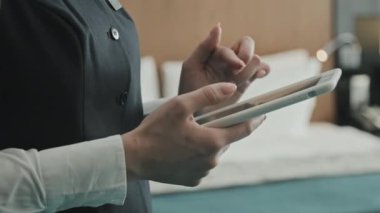 Modern otel odasının içinde dijital tablet kullanan otel müdürünün tanınmayan kadın elinin orta kesimine yakın çekim.