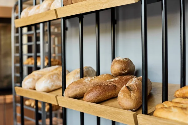 Varios panes de pan fresco en estante de madera en panadería —  Fotos de Stock