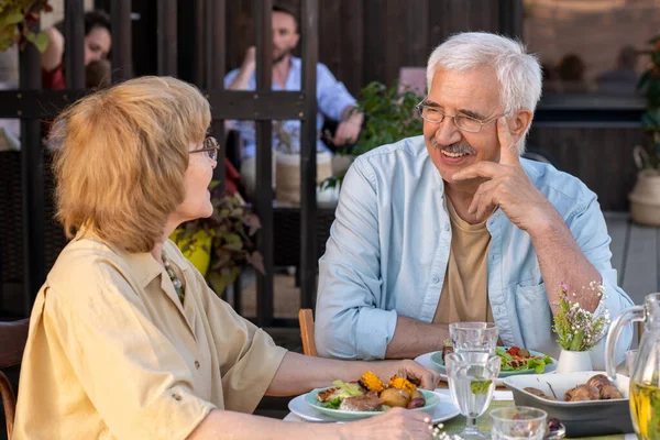 Alegre hombre mayor y su esposa discutiendo algo por la cena al aire libre —  Fotos de Stock