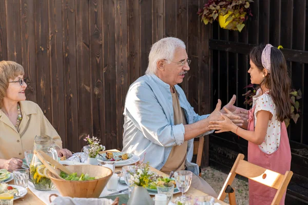 Зрелый человек играет с внучкой за обслуживающим столом — стоковое фото