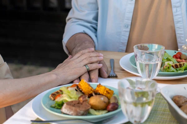 Händer mogna tillgivna par sitter vid serverat bord vid middagen — Stockfoto