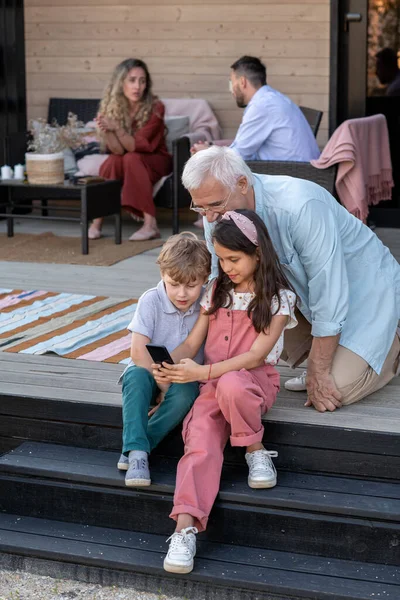 Two kids and their grandfather talking through video chat — Stock Photo, Image