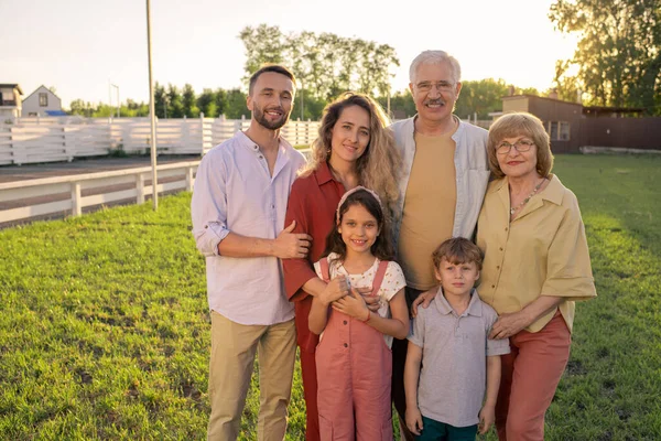 Большая семья из трех поколений стоит на зеленой лужайке — стоковое фото