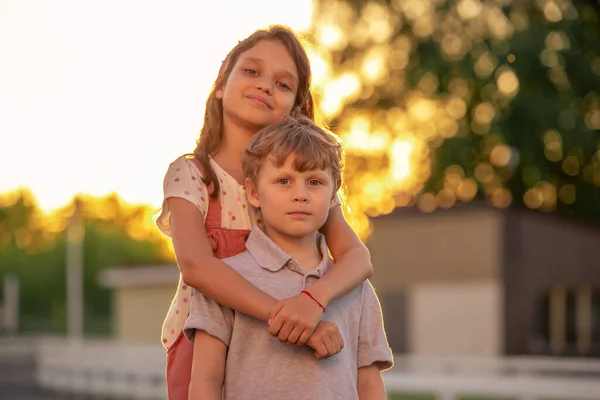 Cute little girl embracing her brother in front of camera — Stock Photo, Image