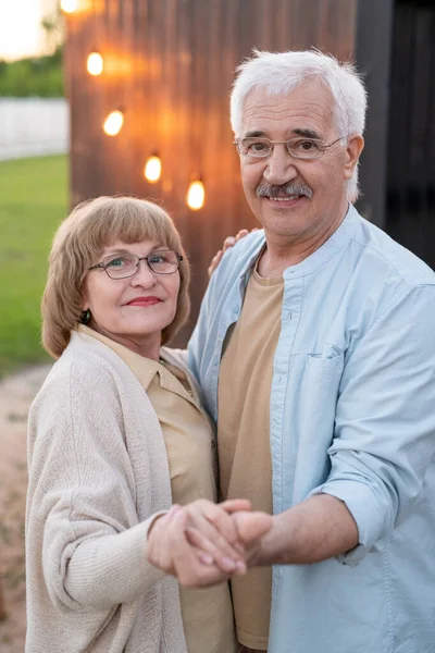 Happy senior man and woman holding by hands in front of camera — Stock Photo, Image