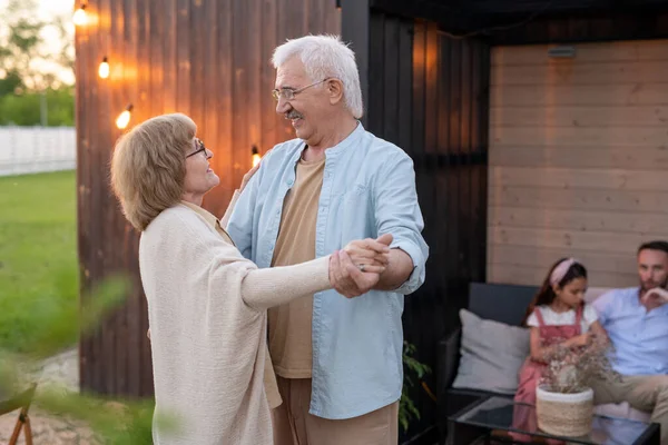 Happy romantic seniors dancing in front of camera with man and girl on background — Stock Photo, Image