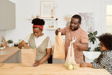 Genç çift kağıt torbalardan yiyecek almaya gidiyor.