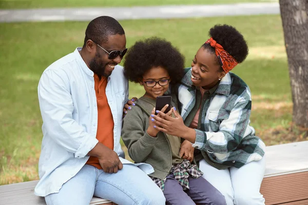 Gelukkig ouders en hun zoon op zoek naar smartphone scherm — Stockfoto