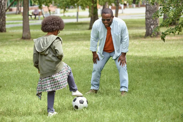 Menino e seu pai jogando futebol no gramado verde — Fotografia de Stock