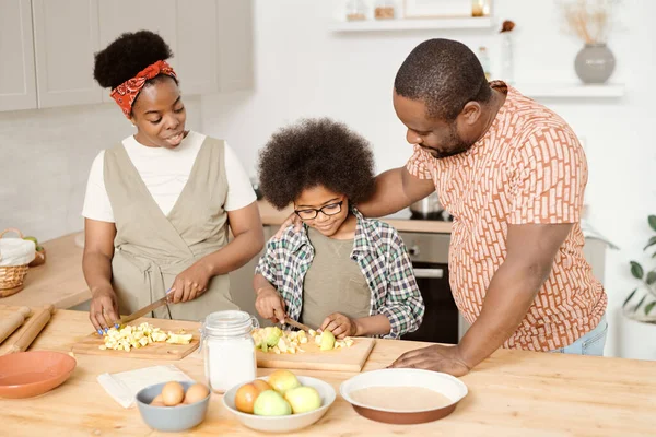 Jonge familie van drie bereiden ontbijt door keukentafel — Stockfoto