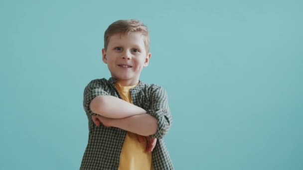 Kollarını Kavuşturup Mavi Arka Planda Kameraya Gülümseyen Yaşındaki Sevimli Çocuğun — Stok video
