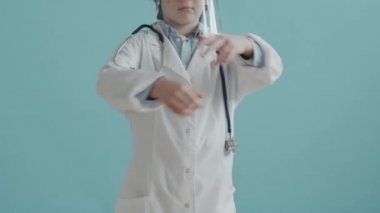 Beyaz önlüklü ve yüz maskeli ciddi bir çocuğun portre fotoğrafını kaldır. Kollarını çapraz yapıp kameraya poz ver.