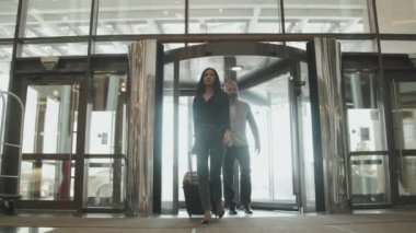 Düşük açılı, bavullu modern çiftin giriş yapmak için lüks bir otele girerken çekilmiş bir fotoğrafı.