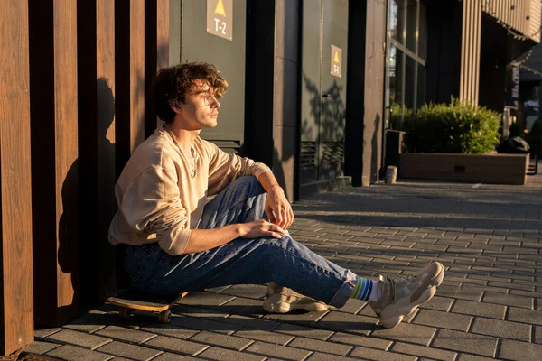 Teenager-Skateboarder sitzt an Wand am Gehweg — Stockfoto