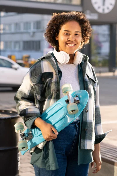 Junger fröhlicher Skateboarder steht in urbaner Umgebung — Stockfoto
