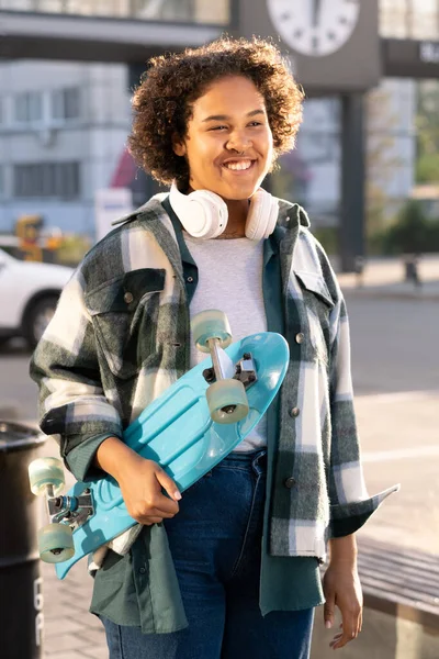 Lachender süßer Teenager mit Skateboard im städtischen Umfeld — Stockfoto