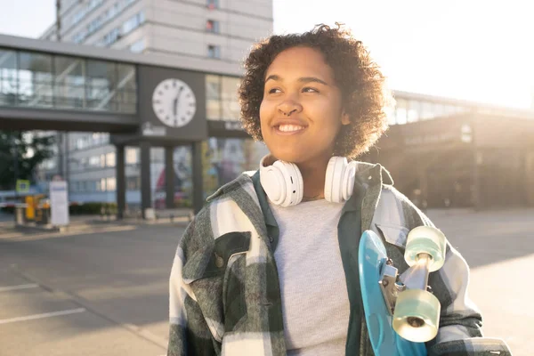 Söt tonåring med skateboard och hörlurar — Stockfoto