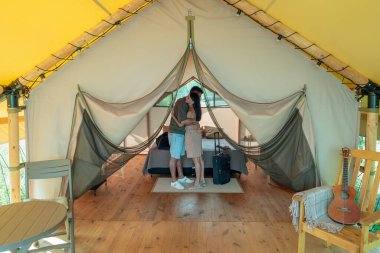 Çift kişilik yatağın yanında duran genç aşık çift.