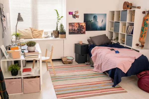 Просторная спальня студента-подростка с кроватью, письменным столом с ноутбуком и другими вещами — стоковое фото