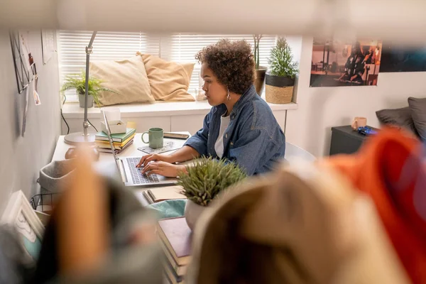 Menina adolescente bonito digitando no teclado do laptop durante a realização de lição de casa — Fotografia de Stock