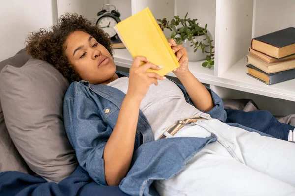Krásná studentka čtení knihy při relaxaci v posteli — Stock fotografie