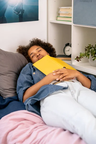 疲惫的少女，胸前翻开书本睡在床上 — 图库照片