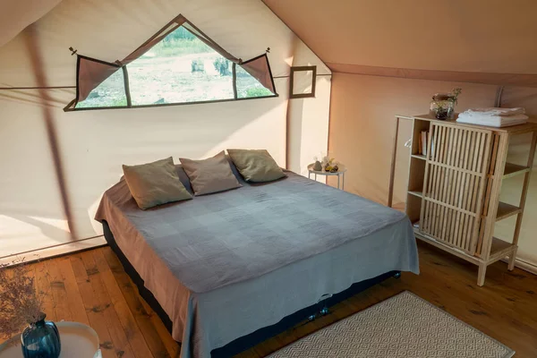 Μεγάλο διπλό κρεβάτι με μαξιλάρια στέκεται στο ξύλινο πάτωμα του υπνοδωματίου — Φωτογραφία Αρχείου