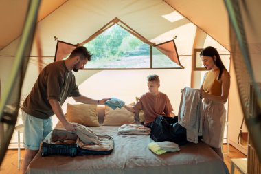 Üç kişilik aile bavullarını ve çantalarını çıkarıyorlar.