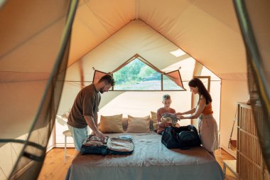 Anne, genç oğluna bir yığın kıyafet veriyor.