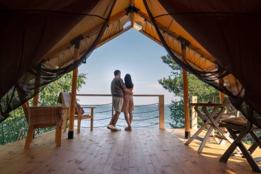 Birbirlerine yakın duran ve okyanusa bakan şehvetli çiftin arka görüntüsü.