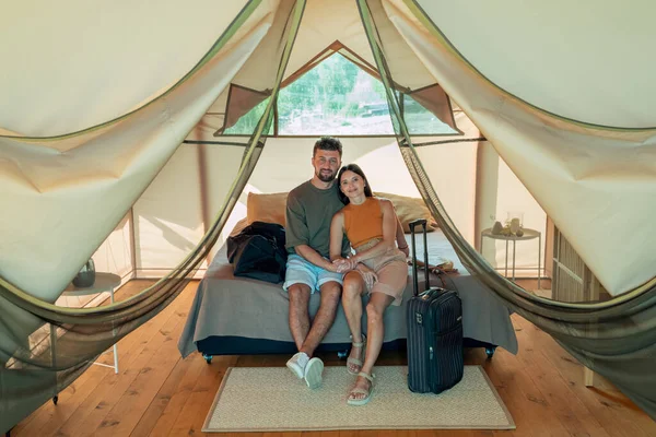 Mutlu, genç, beyaz bir çift glamping evinde yatakta dinleniyor.