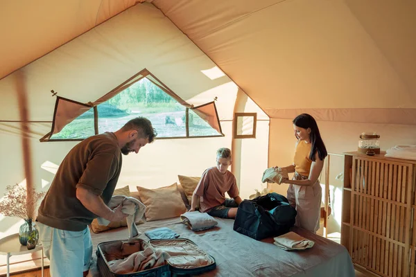 Ebeveynler ve oğulları çantalarından ve çantalarından kıyafetlerini çıkarıyorlar.