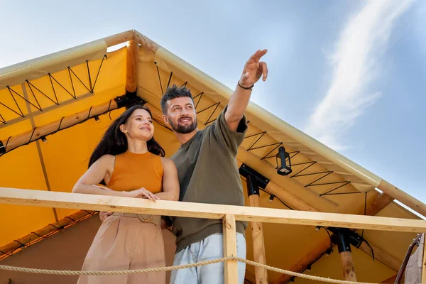 Genç adam, karısının ilgisini çekerken ileri doğru işaret ediyor.