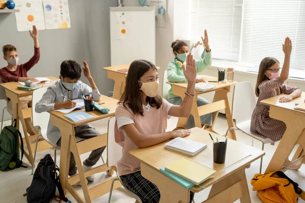 Colegiales inteligentes de diversas etnias levantando las manos —  Fotos de Stock