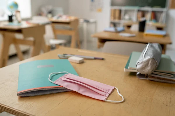 Máscara protectora en copybook y caja de lápiz textil en el escritorio — Foto de Stock