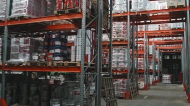 Büyük hırdavatçıların deposundaki raflara istiflenmiş ürünlerin yavaş çekim görüntüleri. Arka planda tanımlanamayan çalışan forklift