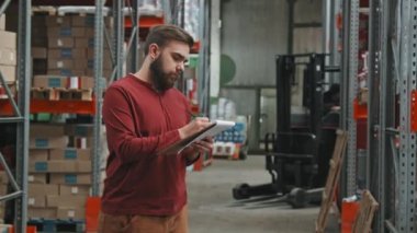 Sakallı erkek işçinin depoda pano stoklayıp kameraya bakarken ki yavaş çekimleri.